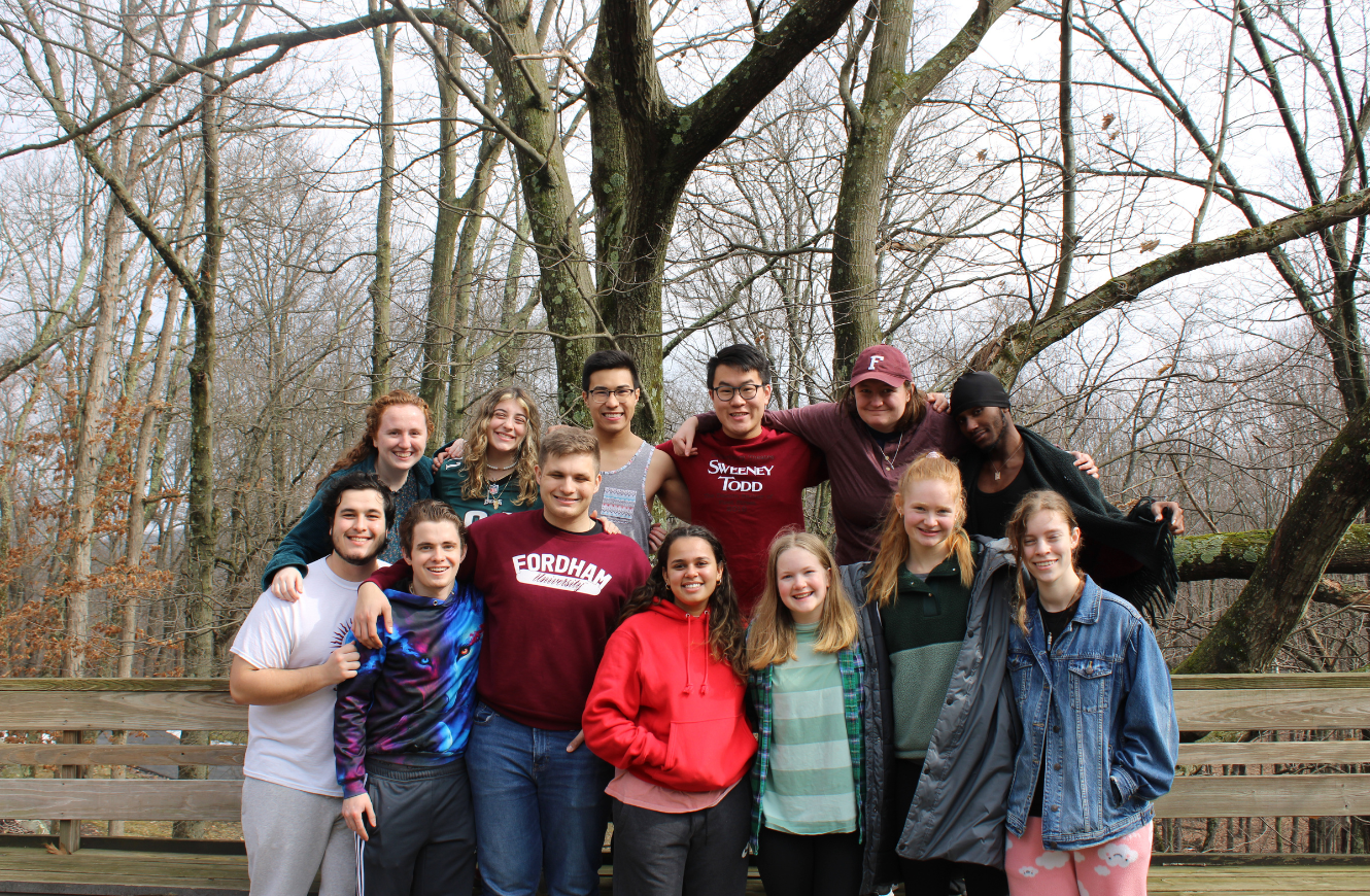 A group of students at the Goshen retreat house posing for a photo in front of trees.