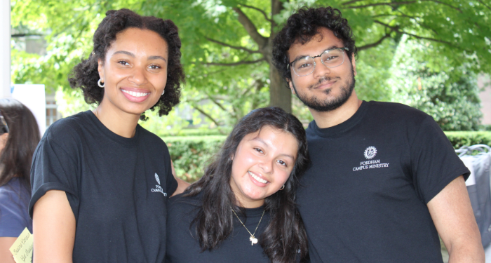 3 students standing next to each other in front of trees, smiling