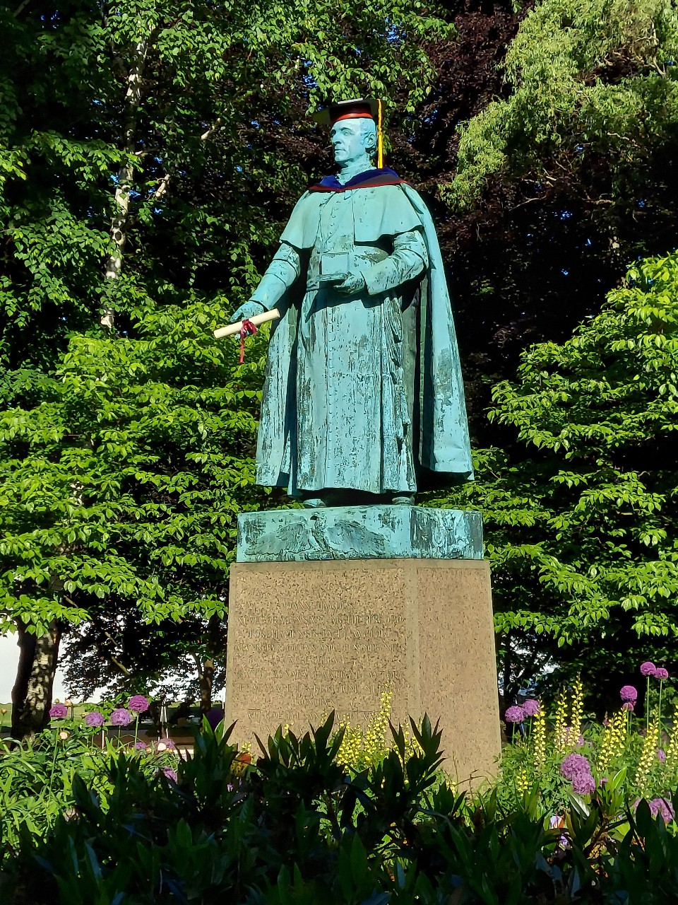 Fordham's Father John Hughes statue with cap and gown for commencement.