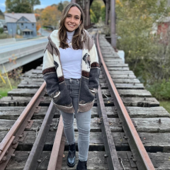 a photo of student eve pollack standing on a ralroad track and smiling.