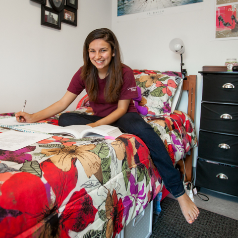 Female student on bed in dorm room - LG