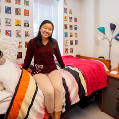 Female student sitting on bed in dorm room - SM