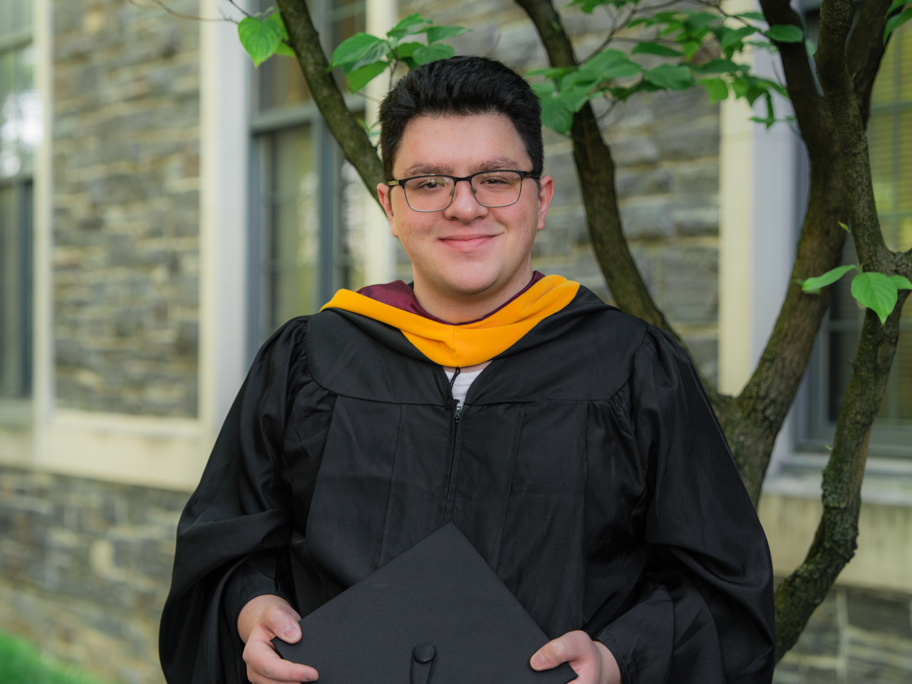 Alban Cotaj standing in front of a tree at Fordham's Commencement at Rose Hill