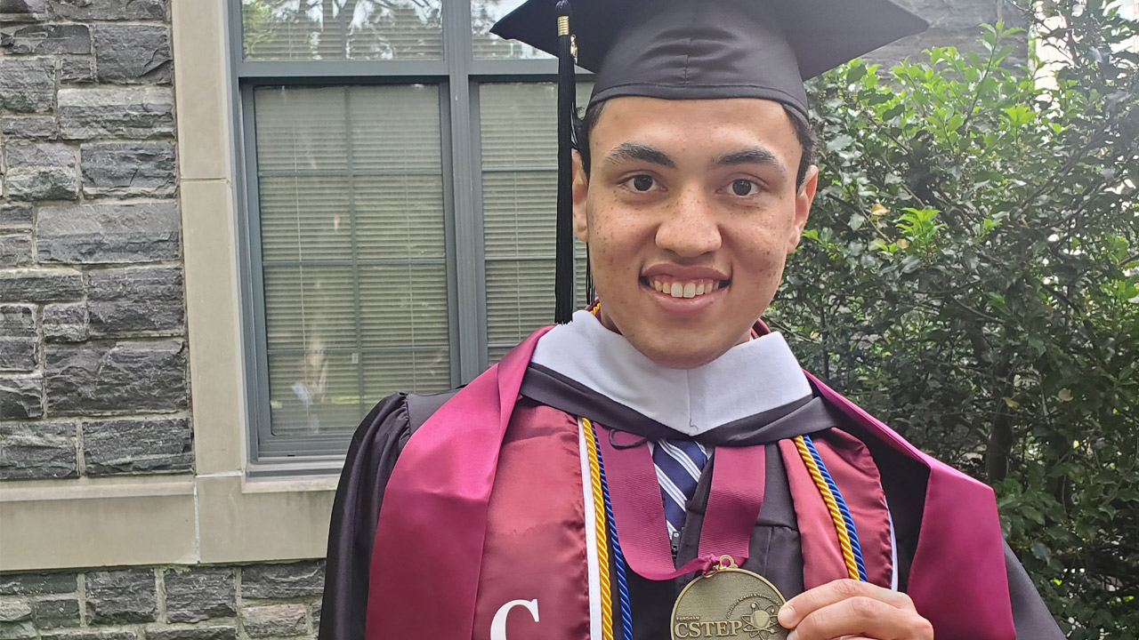 Daniel Hart holding CSTEP medal in graduation gown