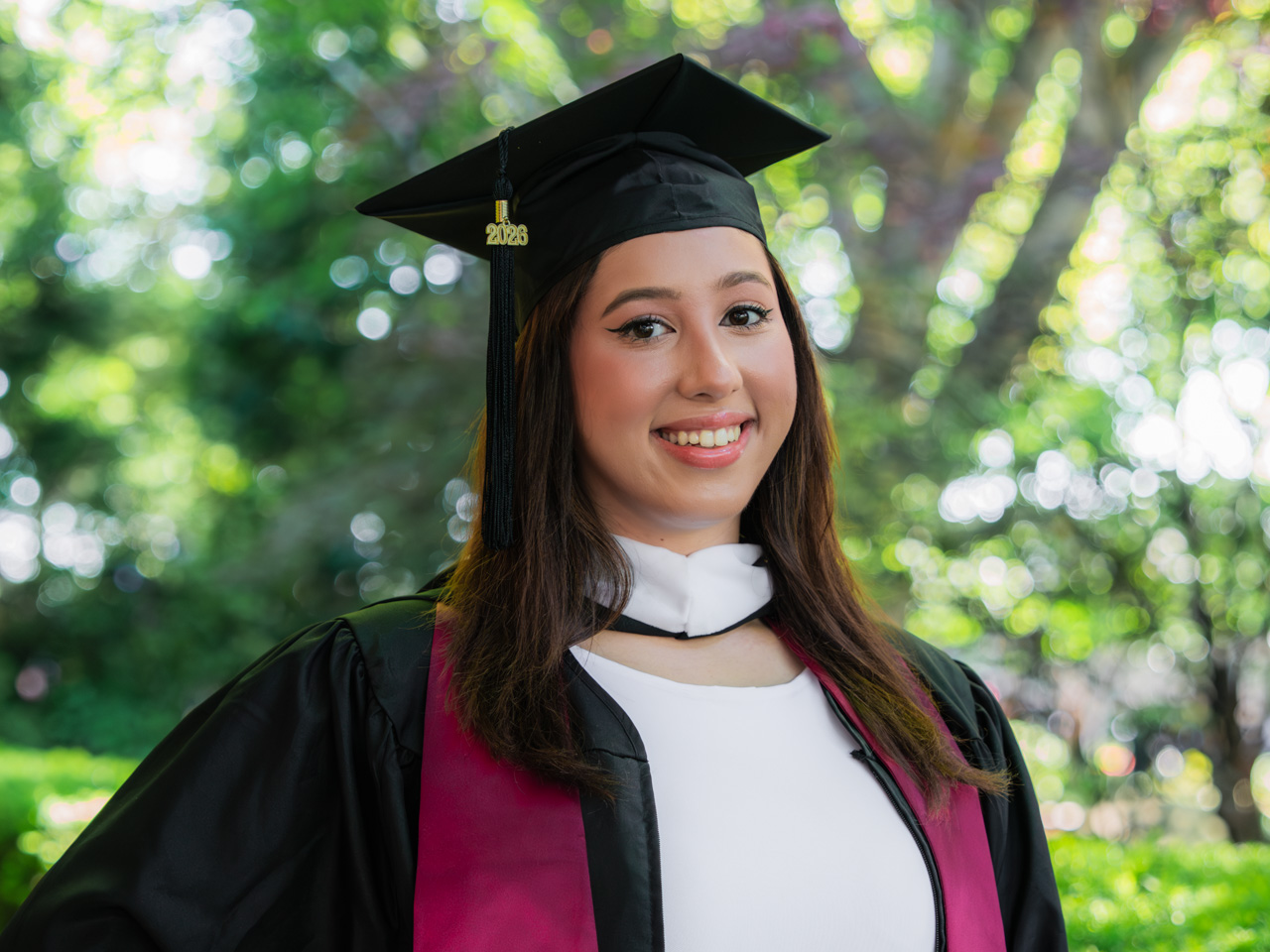Jocelyn Defex standing in front of a tree at Fordham's Commencement at Rose Hill