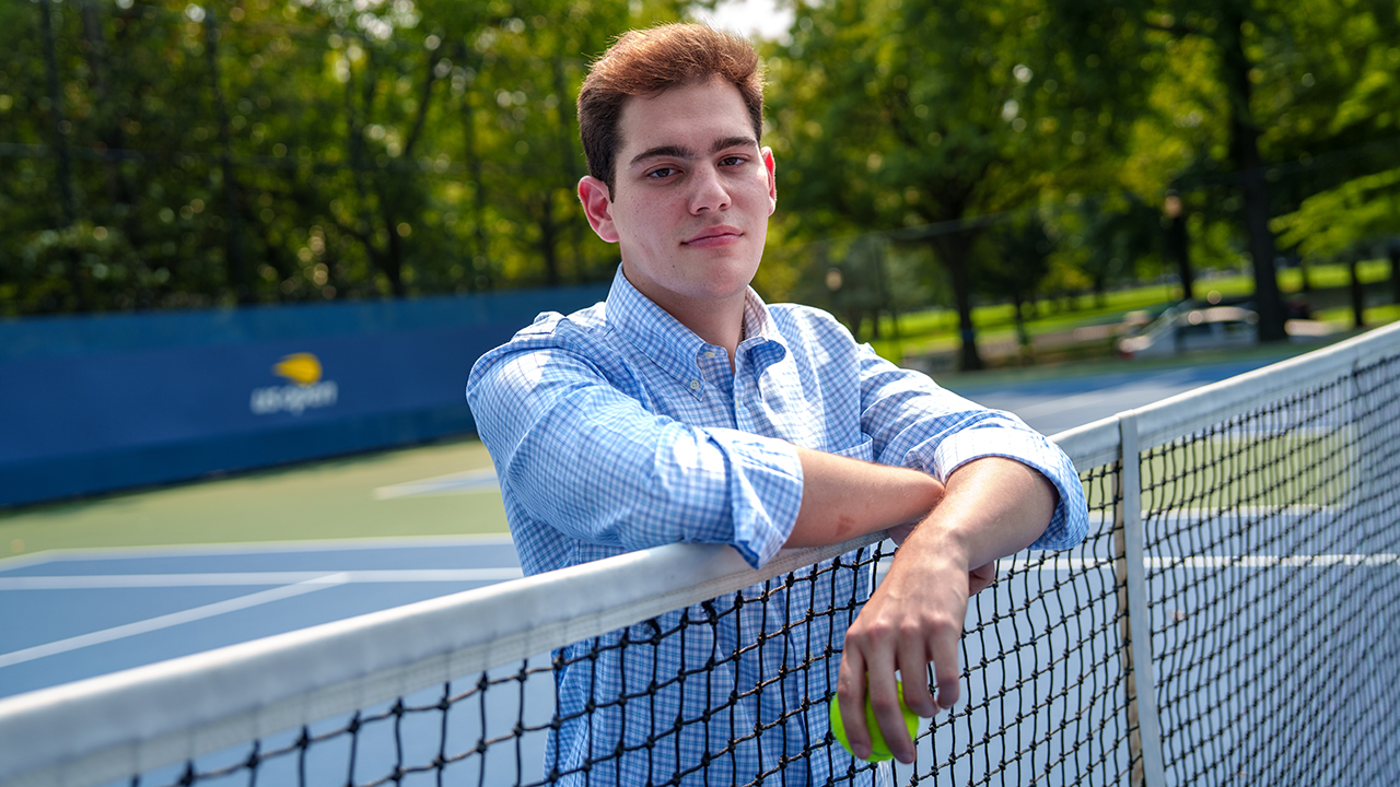 A student poses on a tennis net