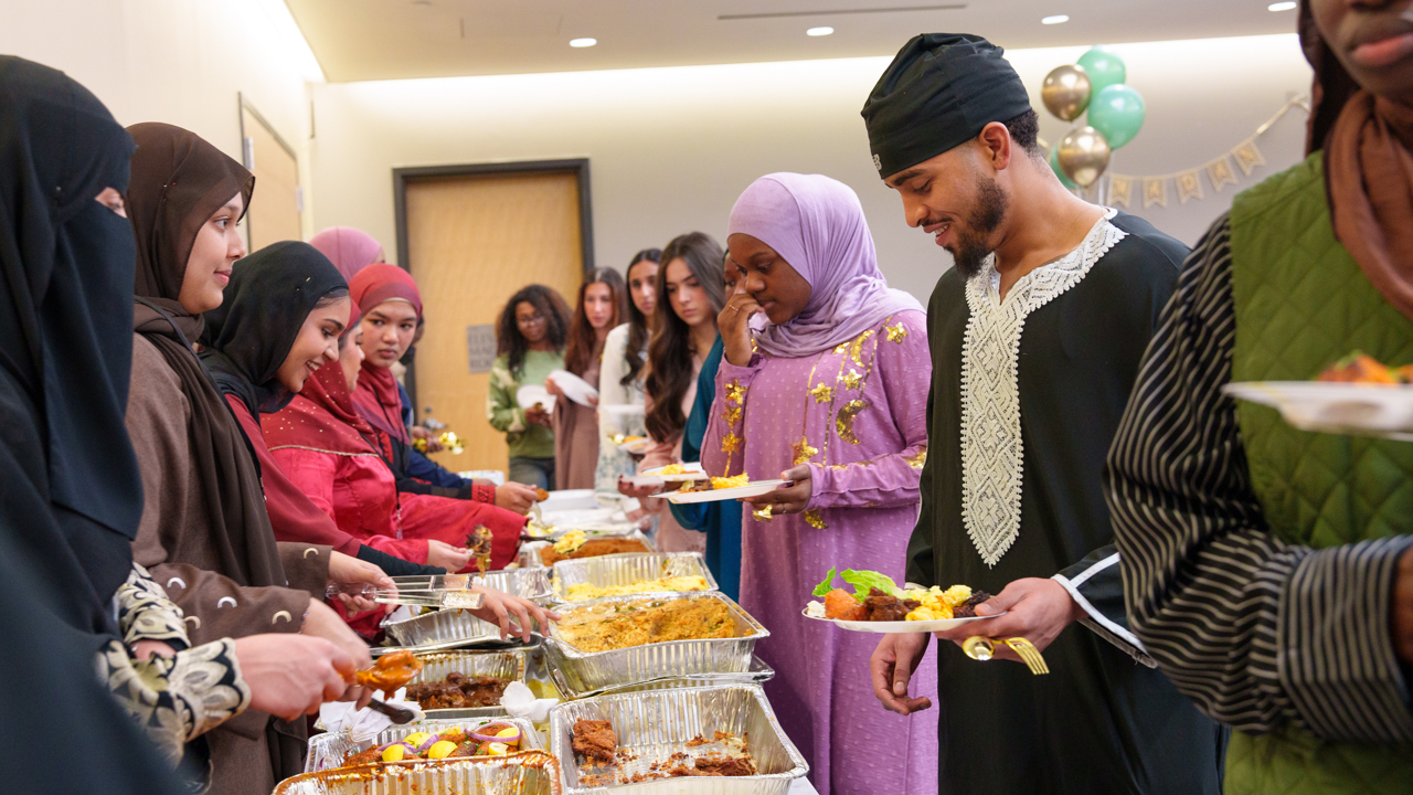 Students hold plates and get food from a buffet.