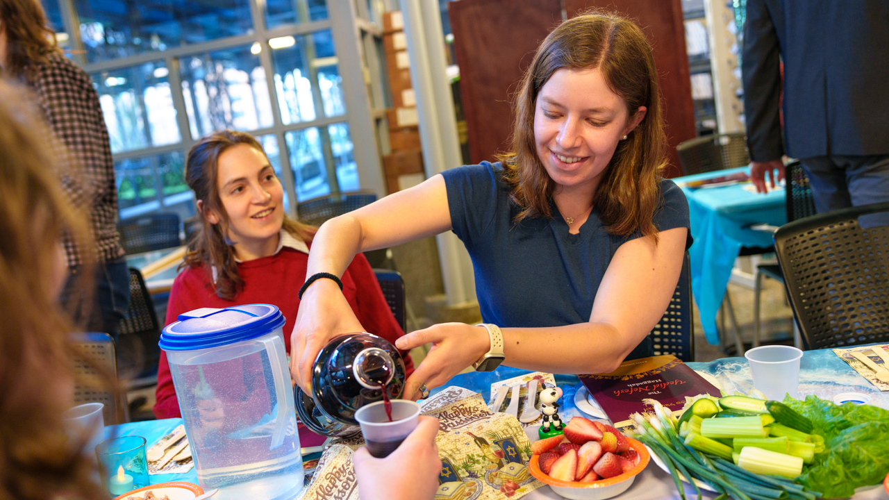 A student pours juice for another student.