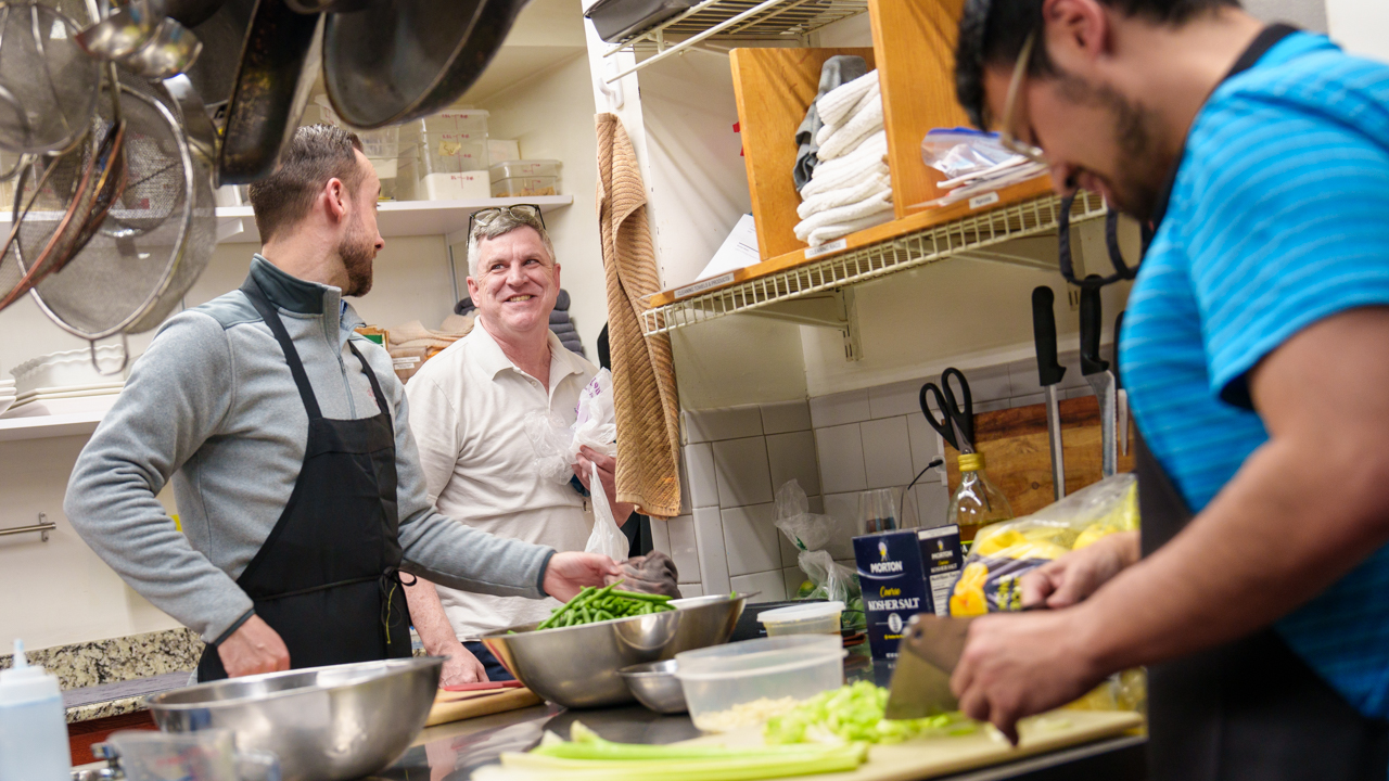 Jesuits prepare food in a kitchen.