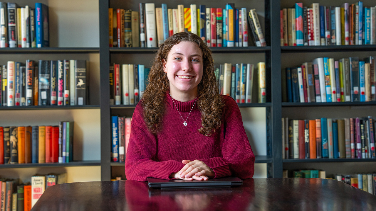 Madison Cossaboom seated at a table in the Center for Fiction