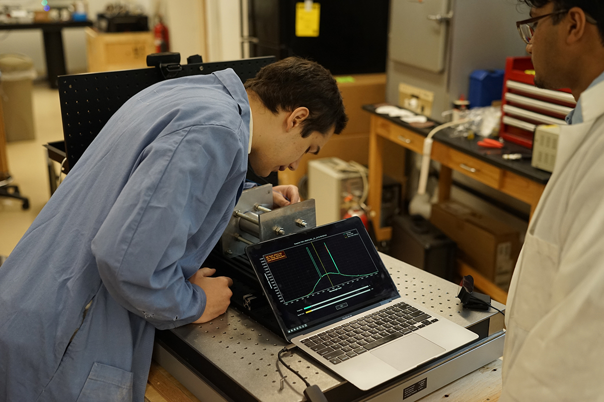 Two students look at a rocket engine in a physics lab.