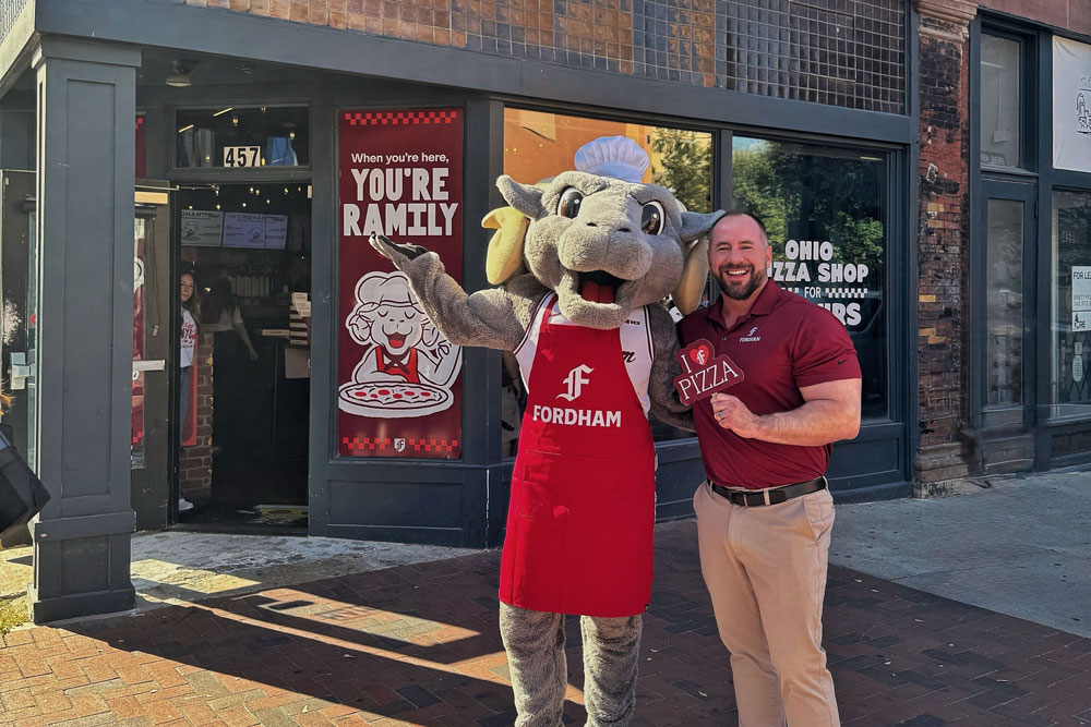 Vice President for Marketing and Communications Justin Bell poses with Ramses in front of the Fordham Pizza Shop in Columbus Ohio