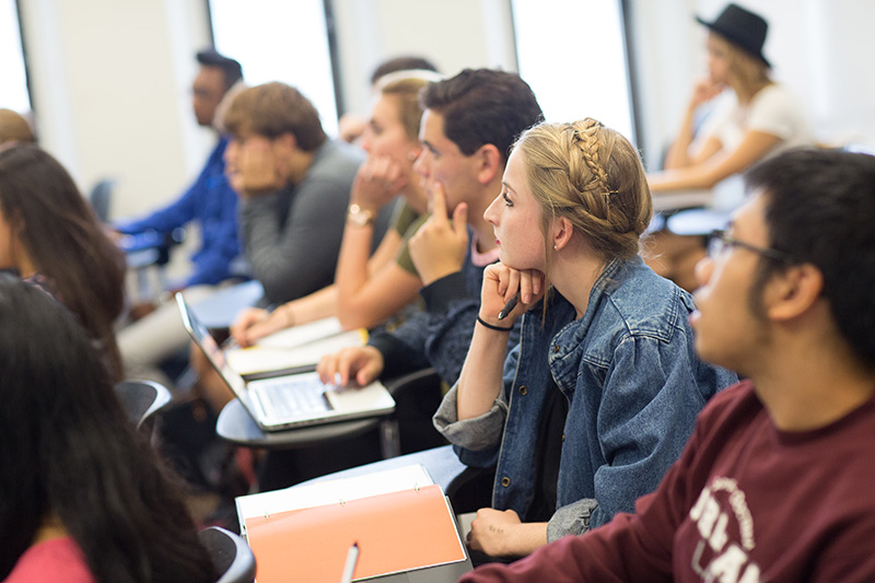 Female student is seated listening to a lecture along with her classmates