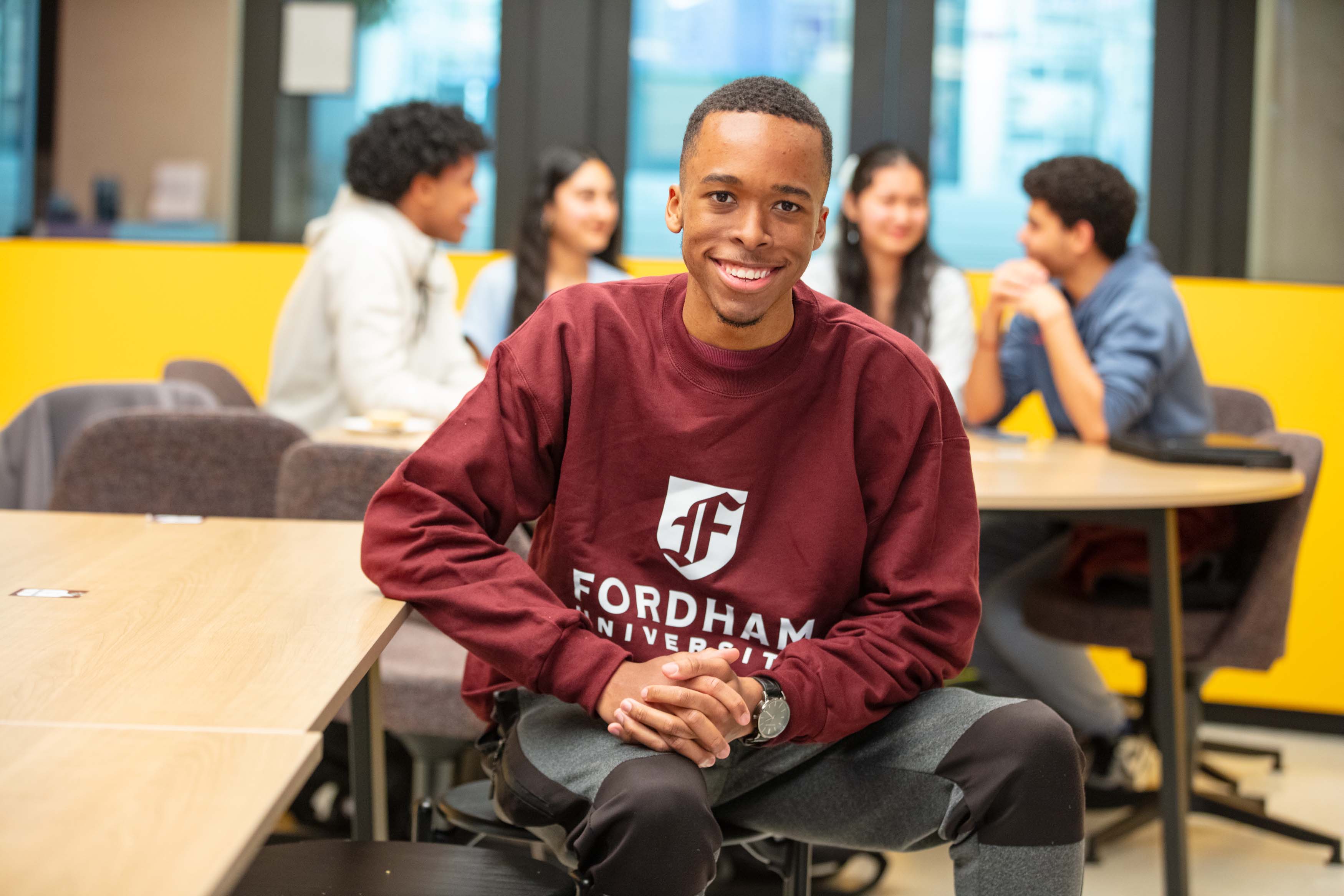 males student sitting smiling at camera with Fordham shirt