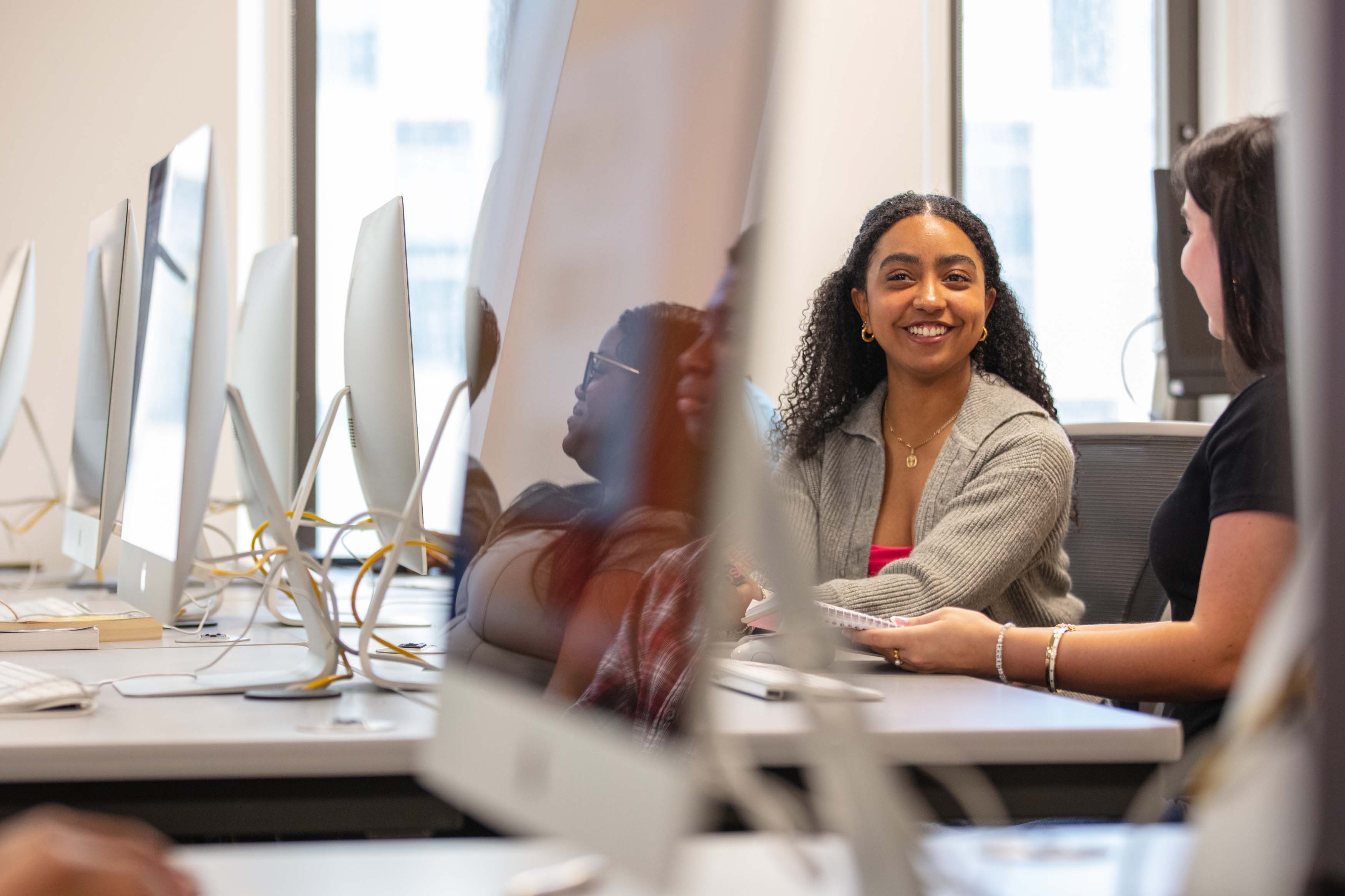 two female students smiling at computers