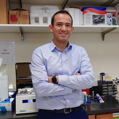 Eduardo Gallo in his lab in Larkin Hall, smiling in a light blue dress shirt with his arms crossed.