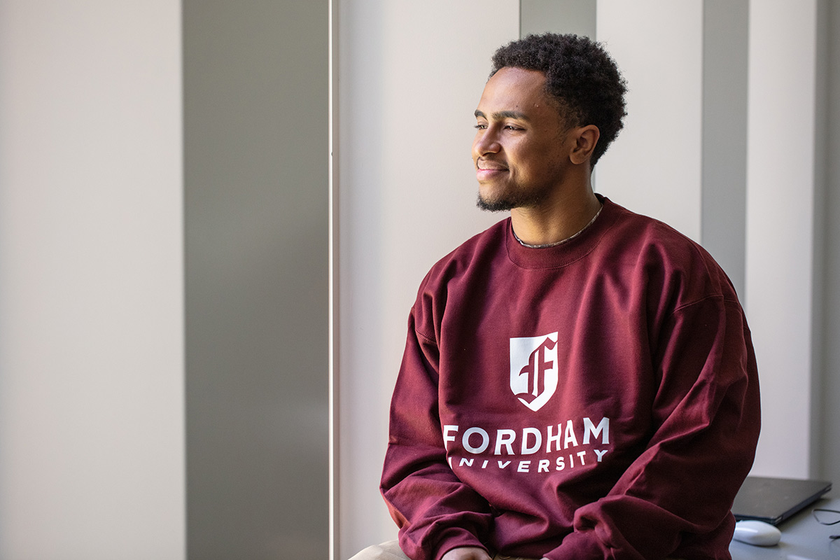 African American student smiling, wearing a Fordham sweatshirt