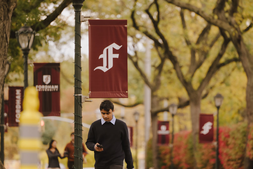 Students walking on the Rose Hill campus with Gothic F banners in the background