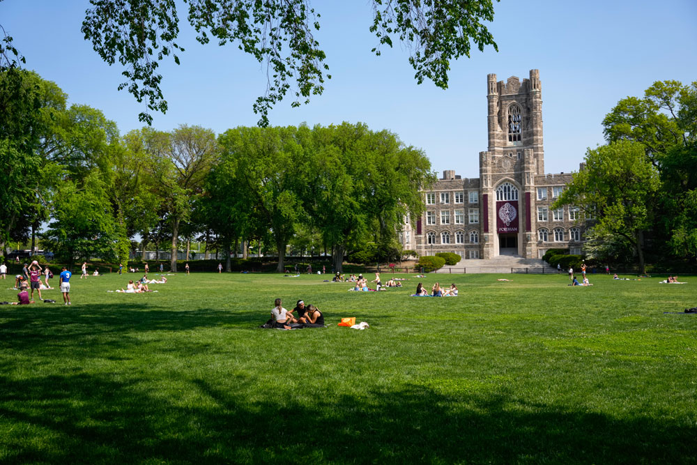 Students enjoy the sun on the large lawn in front of Keating Hall