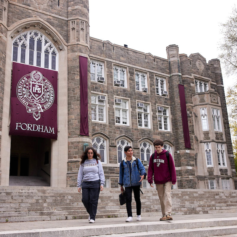 Three students walk down the steps of Keating Hall