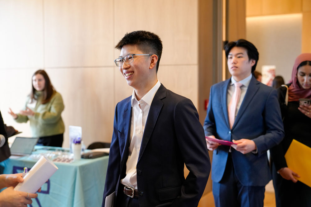 Two male students in suits walk into a career fair on the Rose Hill campus