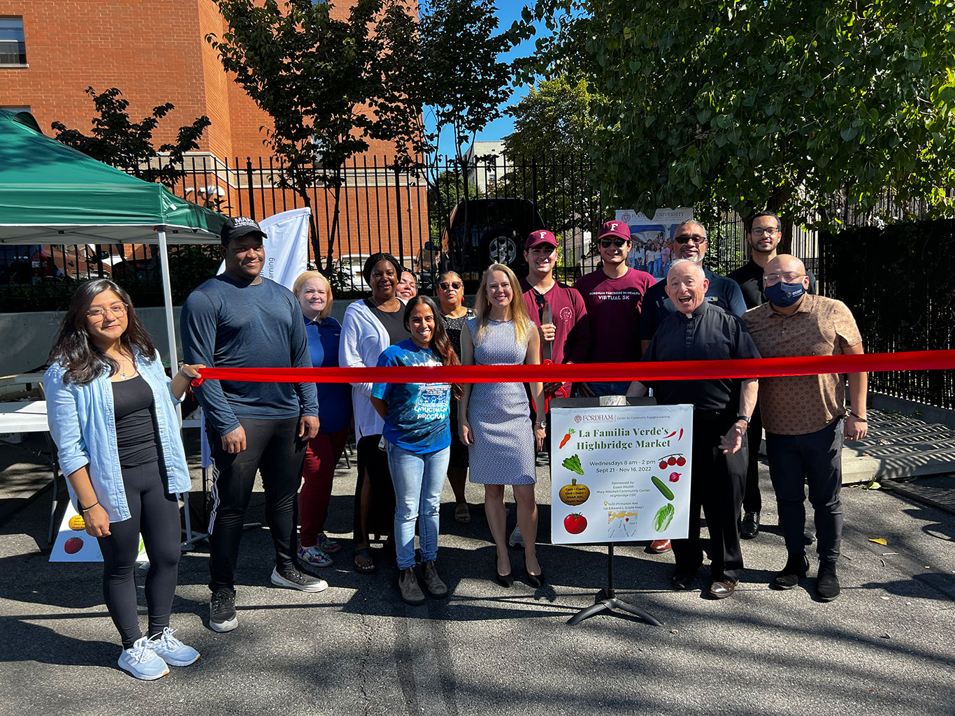 Organizers pose in front of a red ribbon for the grand opening of the La Familia Verde market in Highbridge