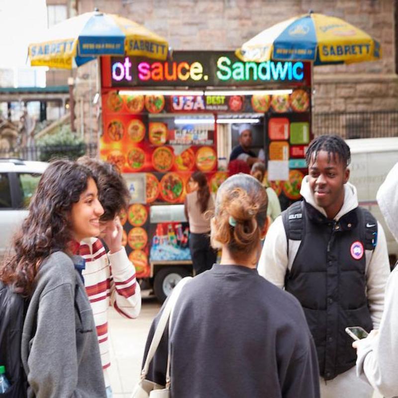 A group of students gather in front of the Halal food cart on the corner of the Lincoln Center campus