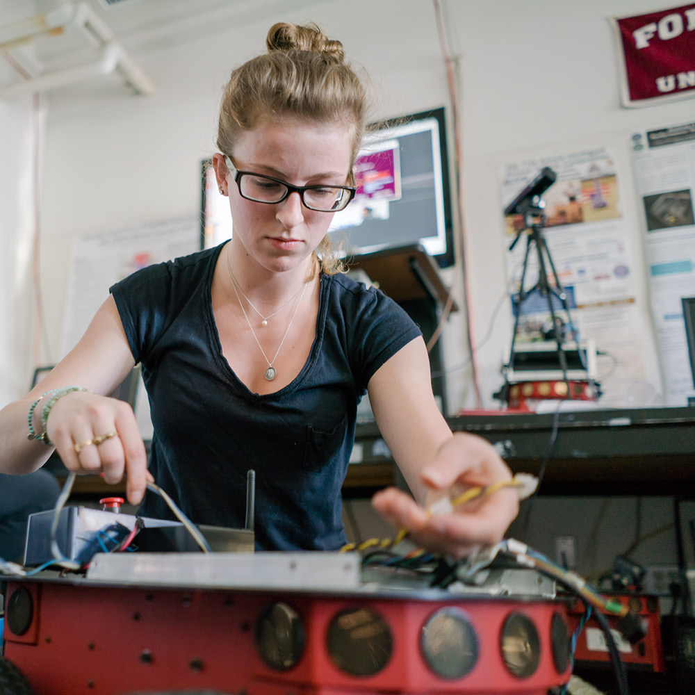 Front View of Female Student Working on Wiring for Robot.