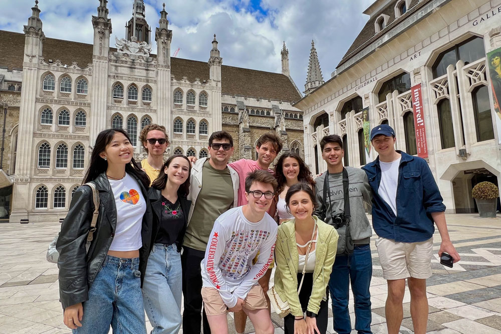 A large group of Fordham students studying at the London campus pose for a picture in a London plaza