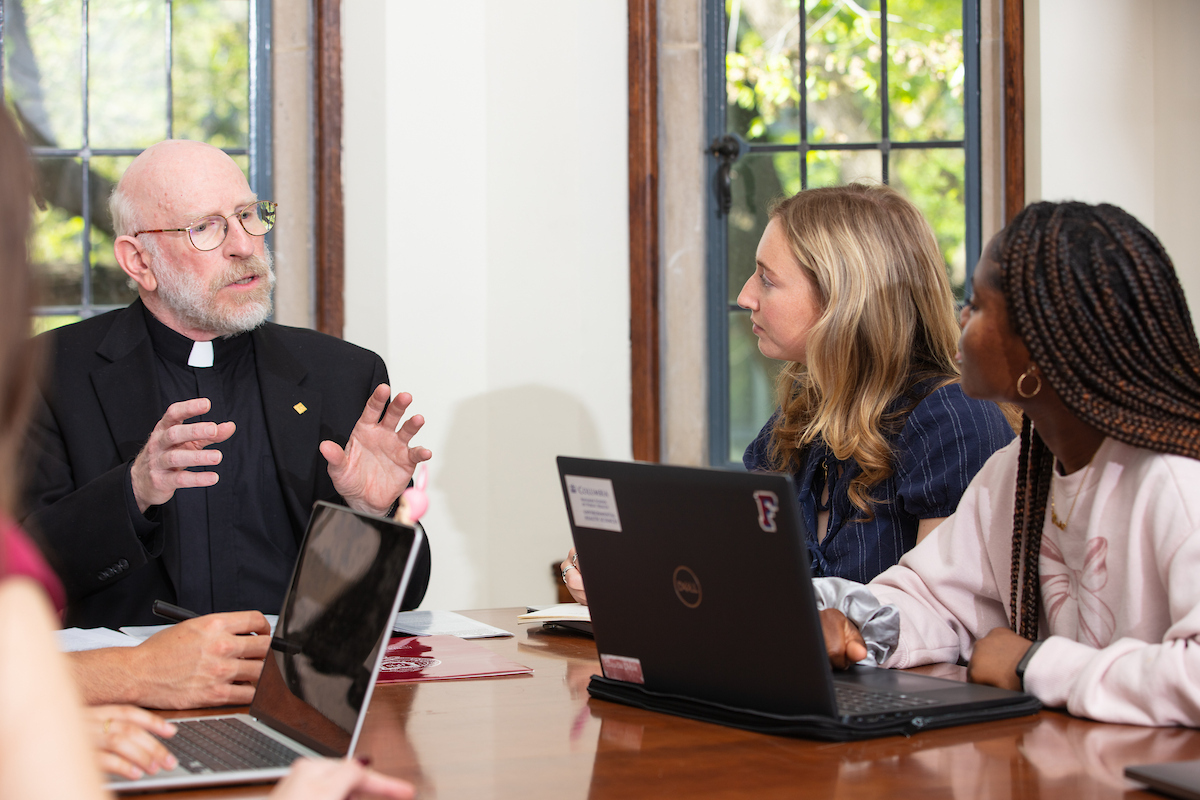 Father Massaro instructs two students in a class in Duane Library