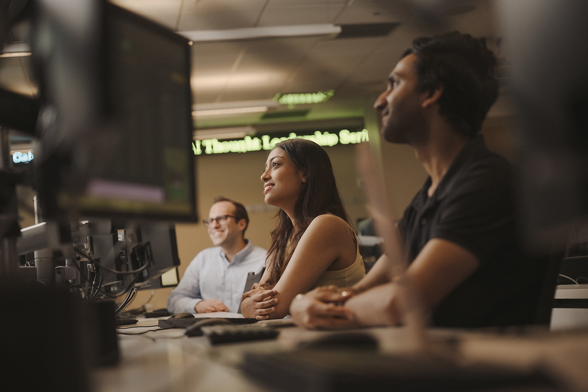 Three students in a classroom working at terminals