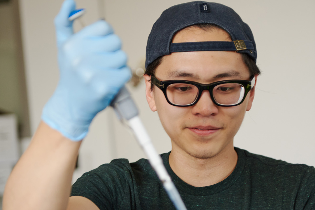 Male student using a syringe in a lab