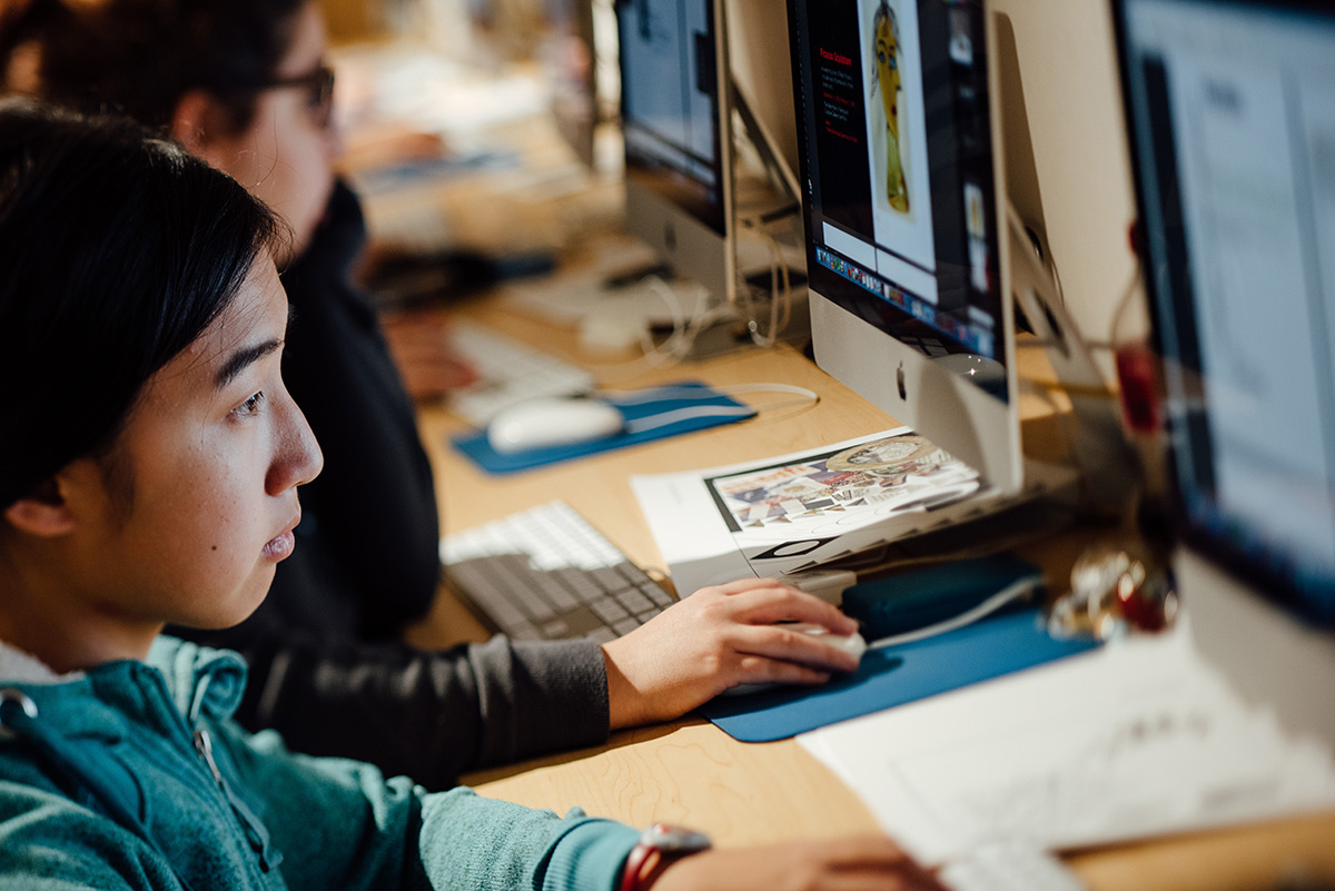Male student doing design work on a desktop in a lab on campus