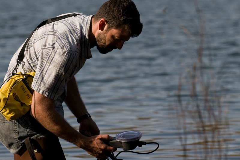 Male student take a water reading out in the field