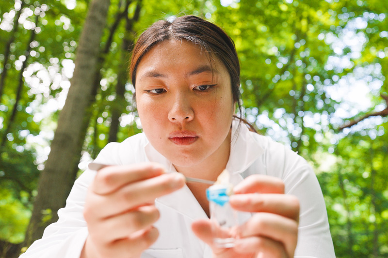 Female student placing a sample into a conainter in the field