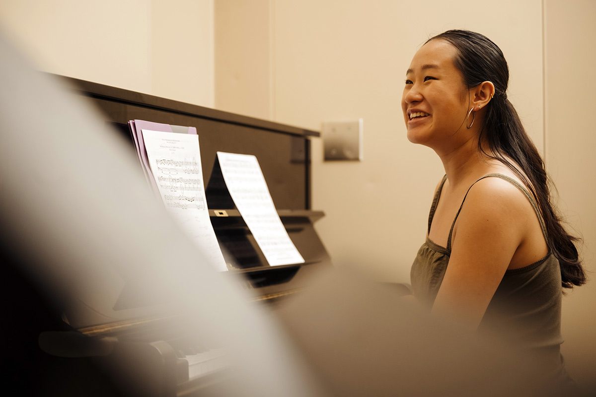 Female student smiles at a piano