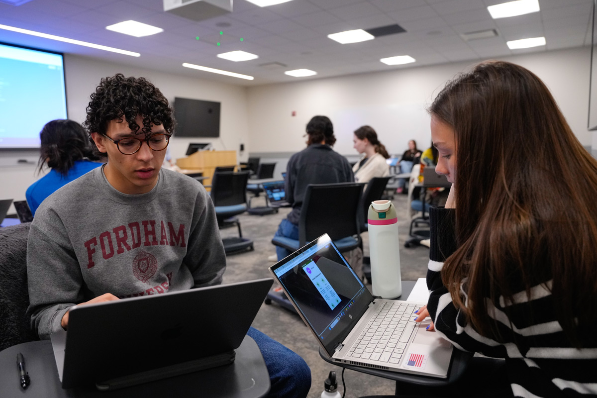 Two students working together on laptops