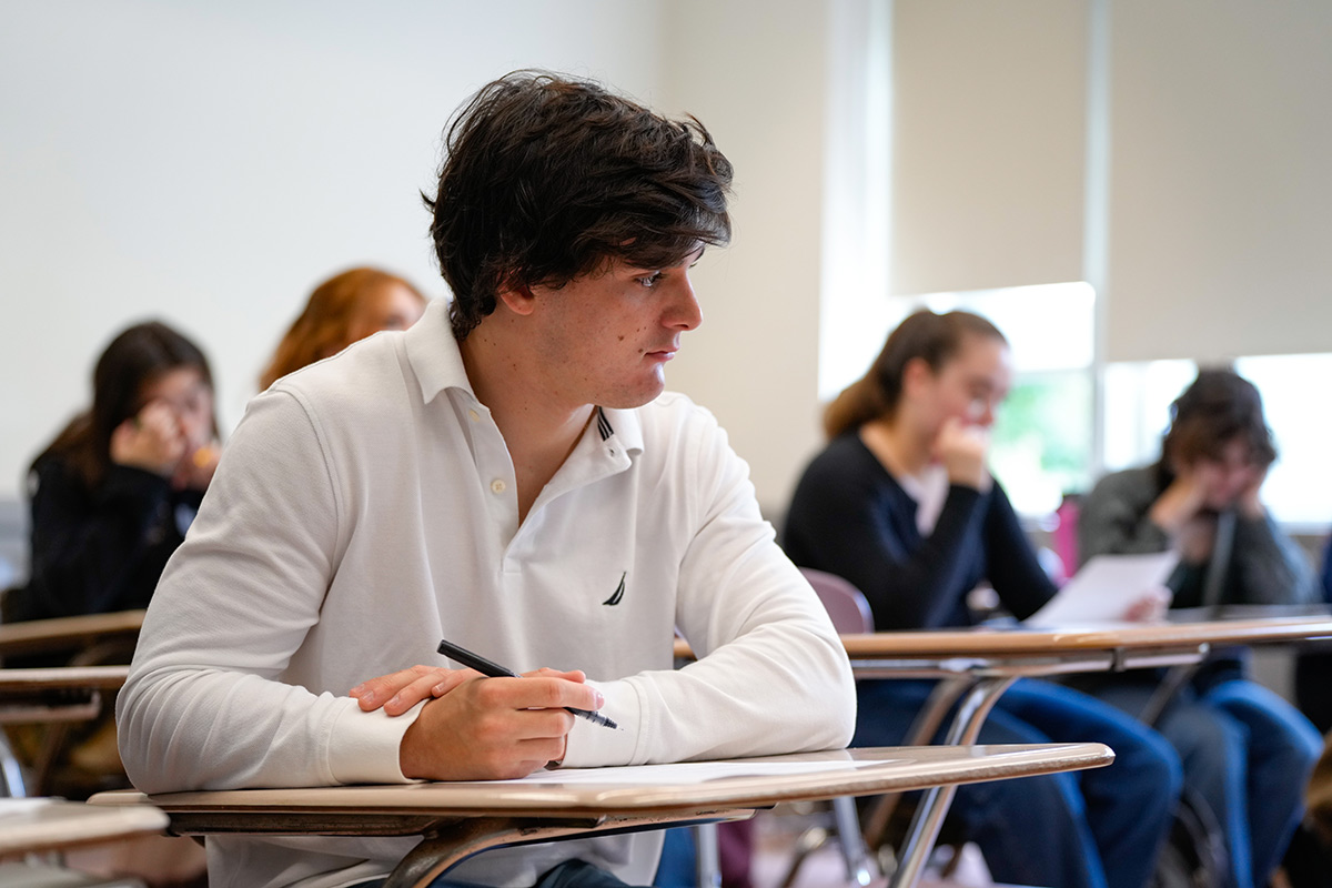 Male student writing at his desk during class