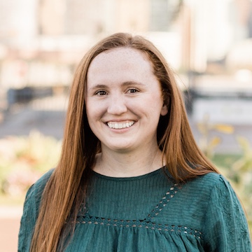 Headshot of employee with green shirt and red hair