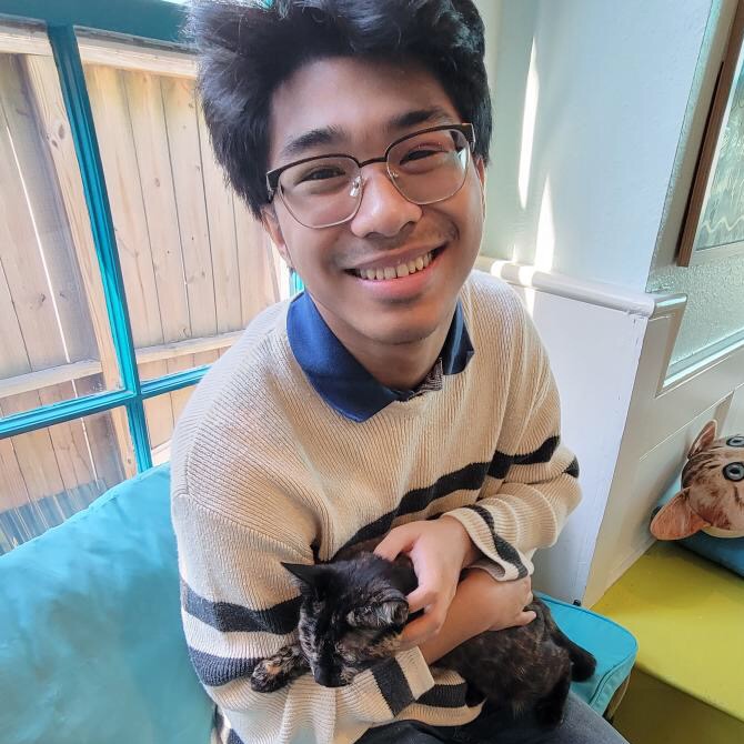 student smiling with cat in his hand