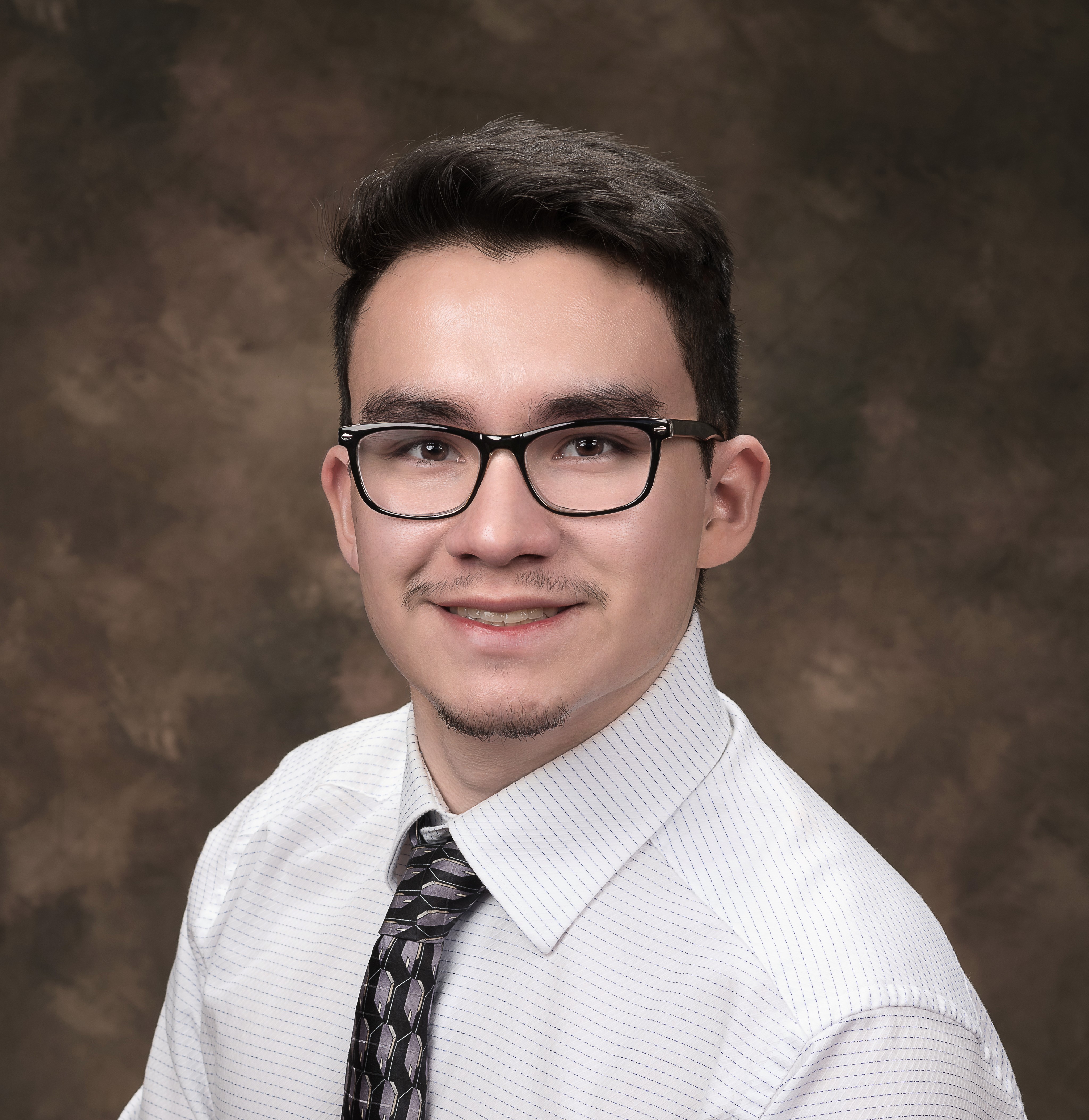 student with a tie and button down shirt smiling for a school picture