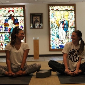 two students sitting together in a yoga pose.