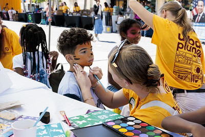 An Urban Plunge student paints a tiger design onto the face of a young child.