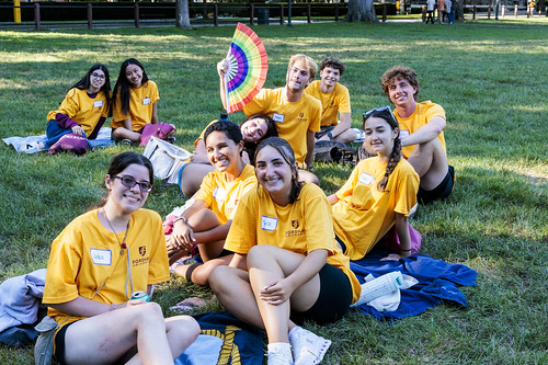 A group of Urban Plunge students sit on a grass lawn and smile together.