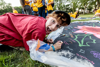 An Urban Plunge student looks happily at the camera as they paint a mural.