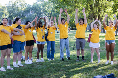 A group of Urban Plunge students in yellow shirts stand in a line with their arms raised above their heads.