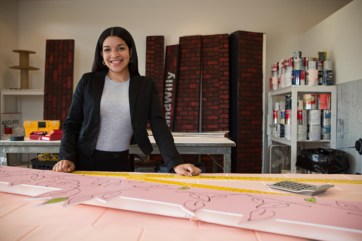 Woman standing in front of desk smiling