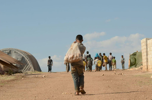 Child refugee walking through a camp © John Wreford/Shutterstock