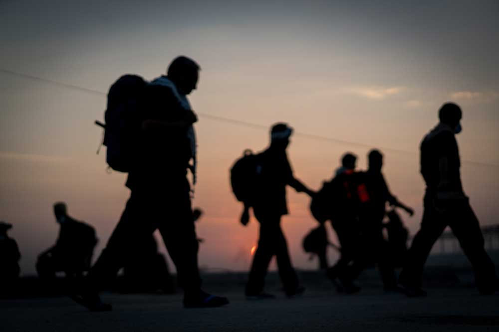 Stock photo of silhouettes of people with backpacks walking at dusk