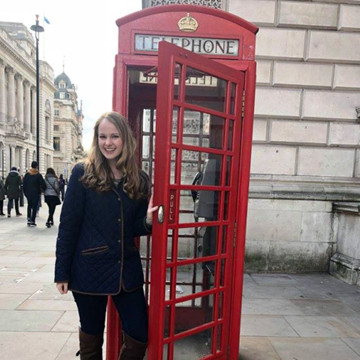 Student in London in Phone Booth Smiling